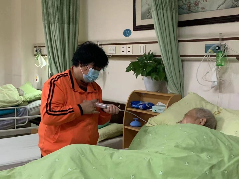 爱以德养老院里,护工正在照料老人.