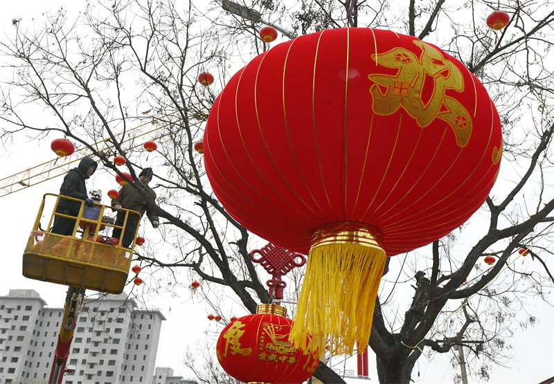 1月13日,工人在唐山市迁西县城区街道旁悬挂灯笼.