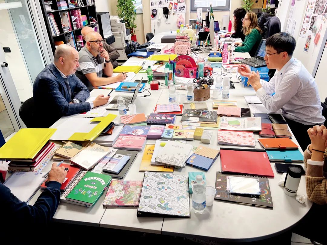 江苏长江纸业的代表向意大利的一家客户介绍公司的新产品，桌子上摆满了他们用三只行李箱带去的样品。图/受访者提供