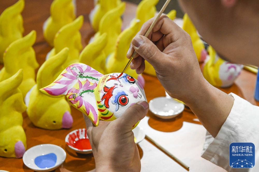 1月16日,河北省玉田县一家泥塑工坊的民间艺人在给生肖兔作品着色.