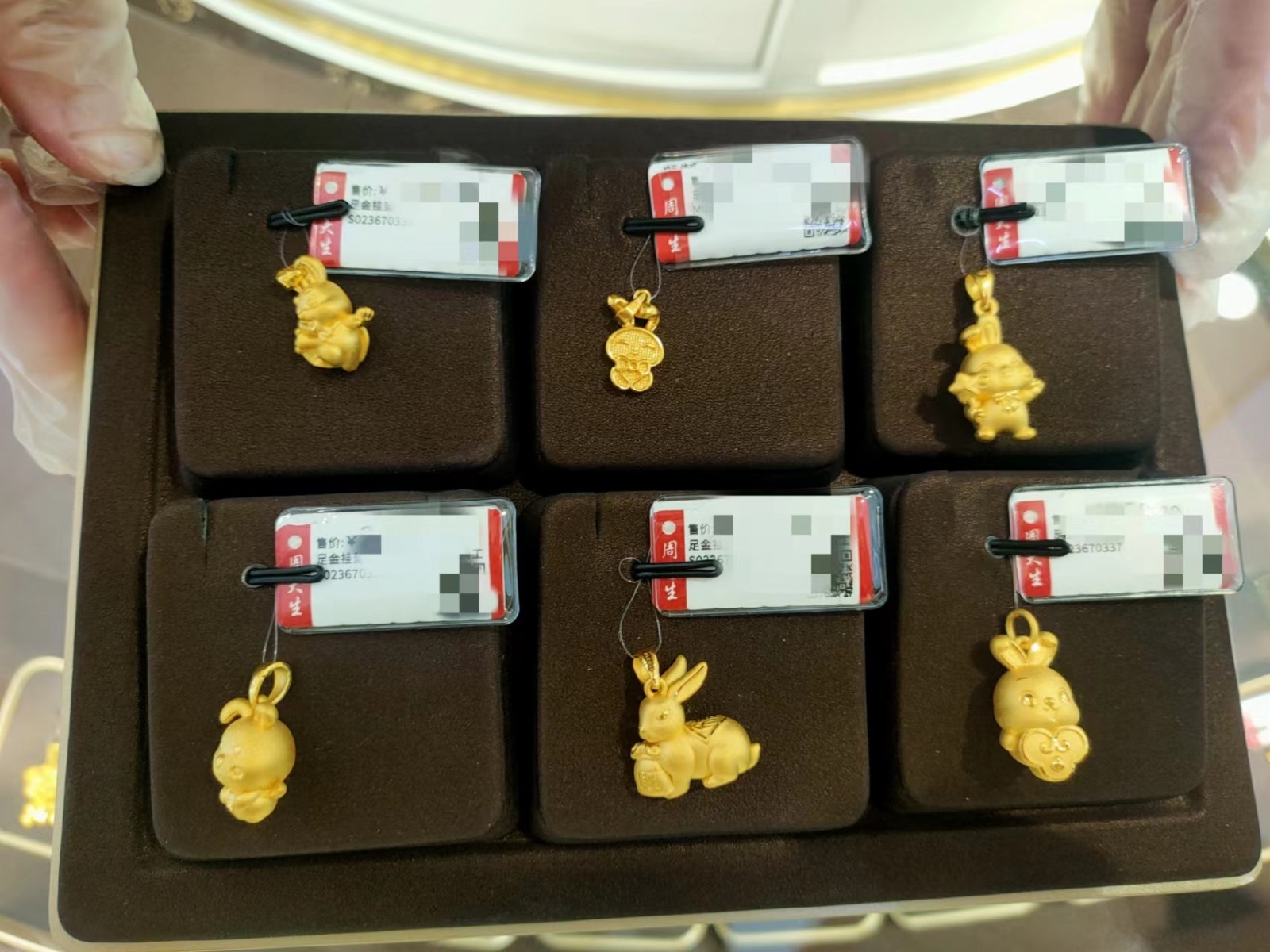 1月17日，周大生柜台的销售人员正在向消费者展示兔年生肖黄金饰品。