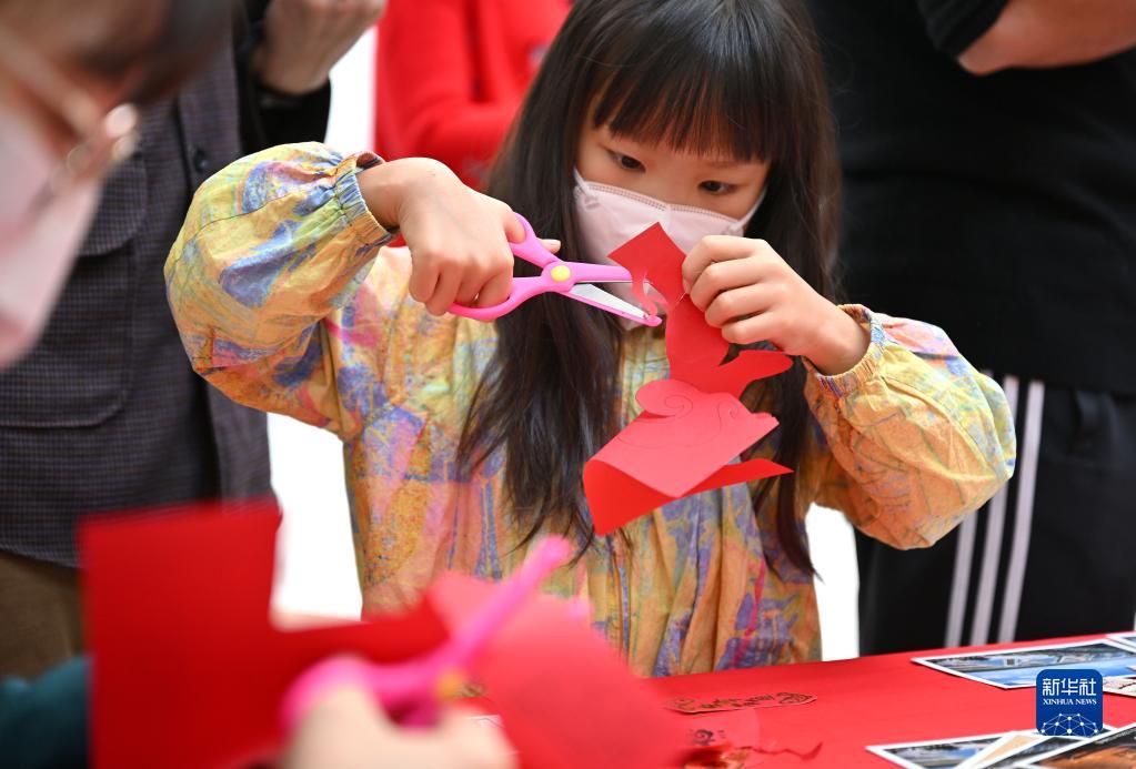 1月19日,在海口美兰国际机场出发大厅,一名小朋友在体验剪纸.
