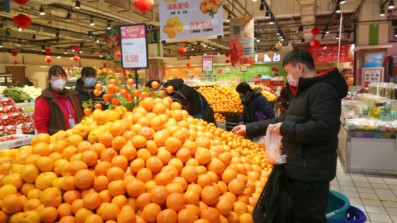超市年货区,群众正在挑选水果.