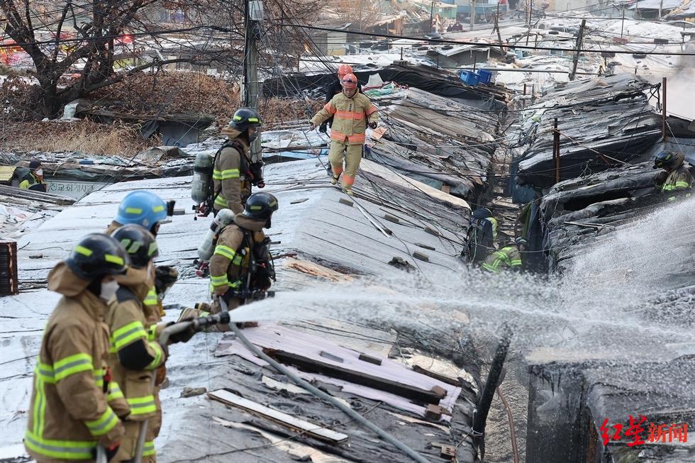 韩国消防员站在棚屋顶，进行灭火工作
