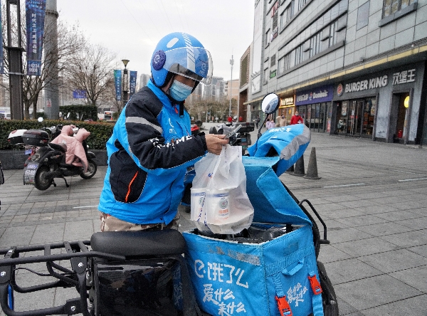 图说:大年三十下午,35岁的饿了吗快递员周洋(女)还在为客户送快递(张