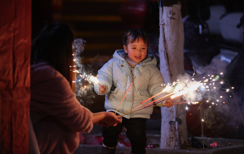 在贵州省黔东南苗族侗族自治州丹寨县,一位母亲陪伴孩子燃放烟花
