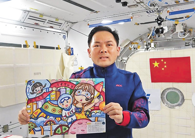 穿着“祥云服”的航天员张陆在展示“天宫画展”青少年绘画作品。中国载人航天工程新闻宣传办公室供图
