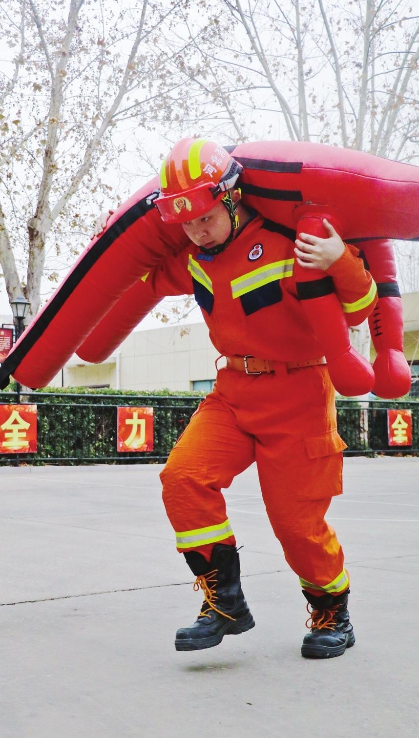 图为消防员负重进行四百米疏散物资训练.