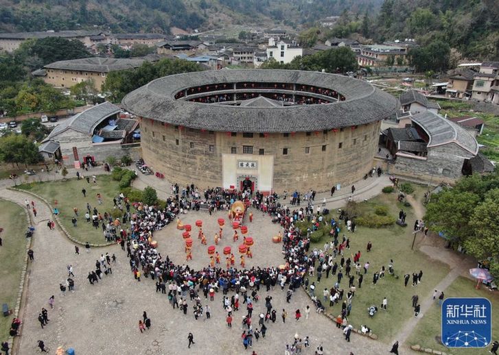 ↑1月25日，游客在福建省龙岩市永定区土楼景区观看民俗表演（无人机照片） 。新华社发（周杨东 摄）