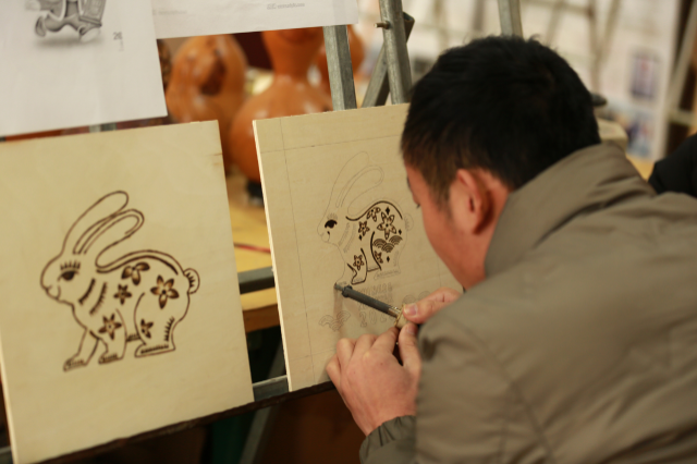 宋士江正在进行木板烙画"大展宏图(兔)"创作.通讯员 毕兴世 摄