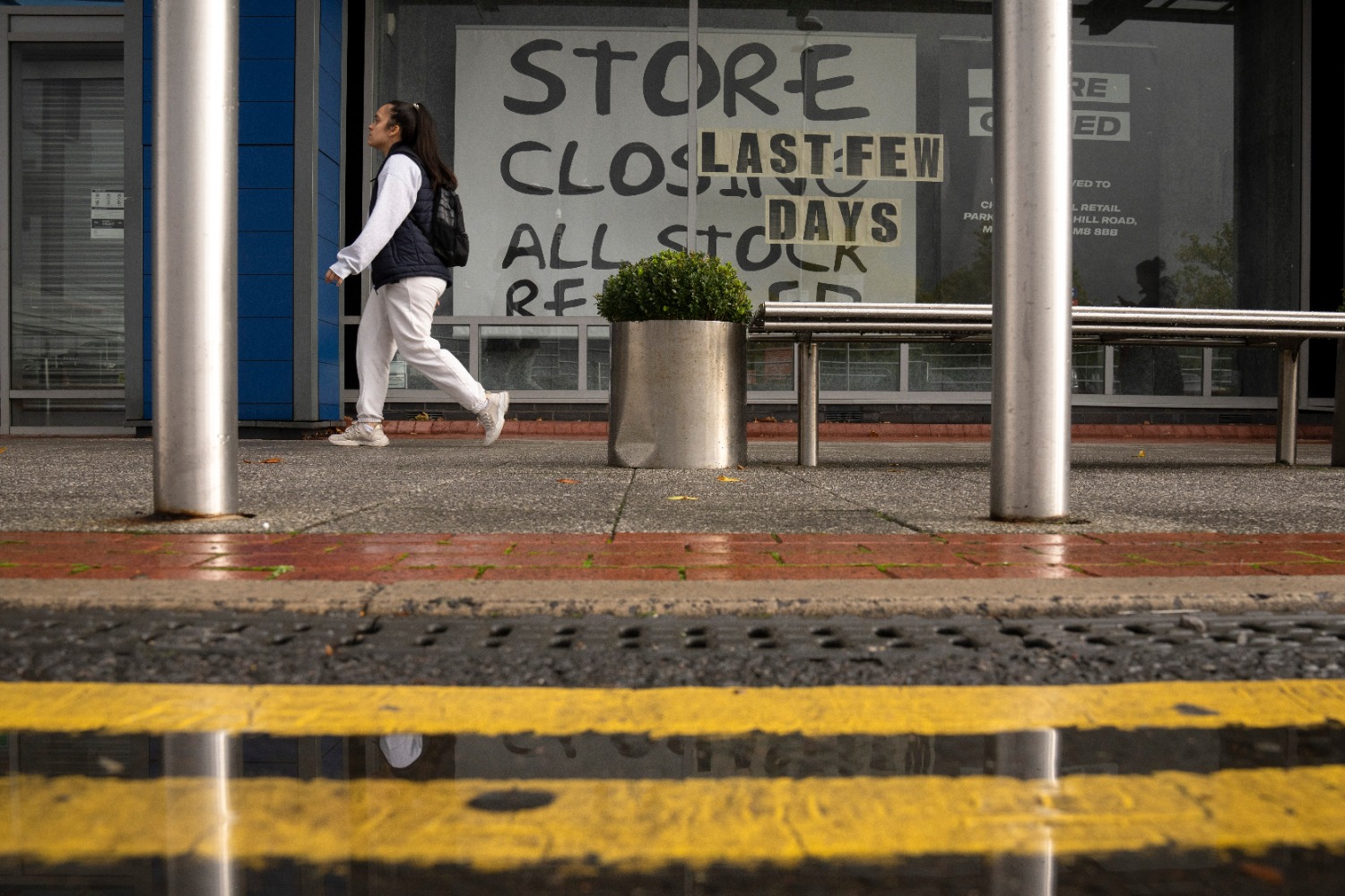 图为在英国曼彻斯特，一名行人走过一家关闭的店铺。（新华社发，乔恩·休珀摄）