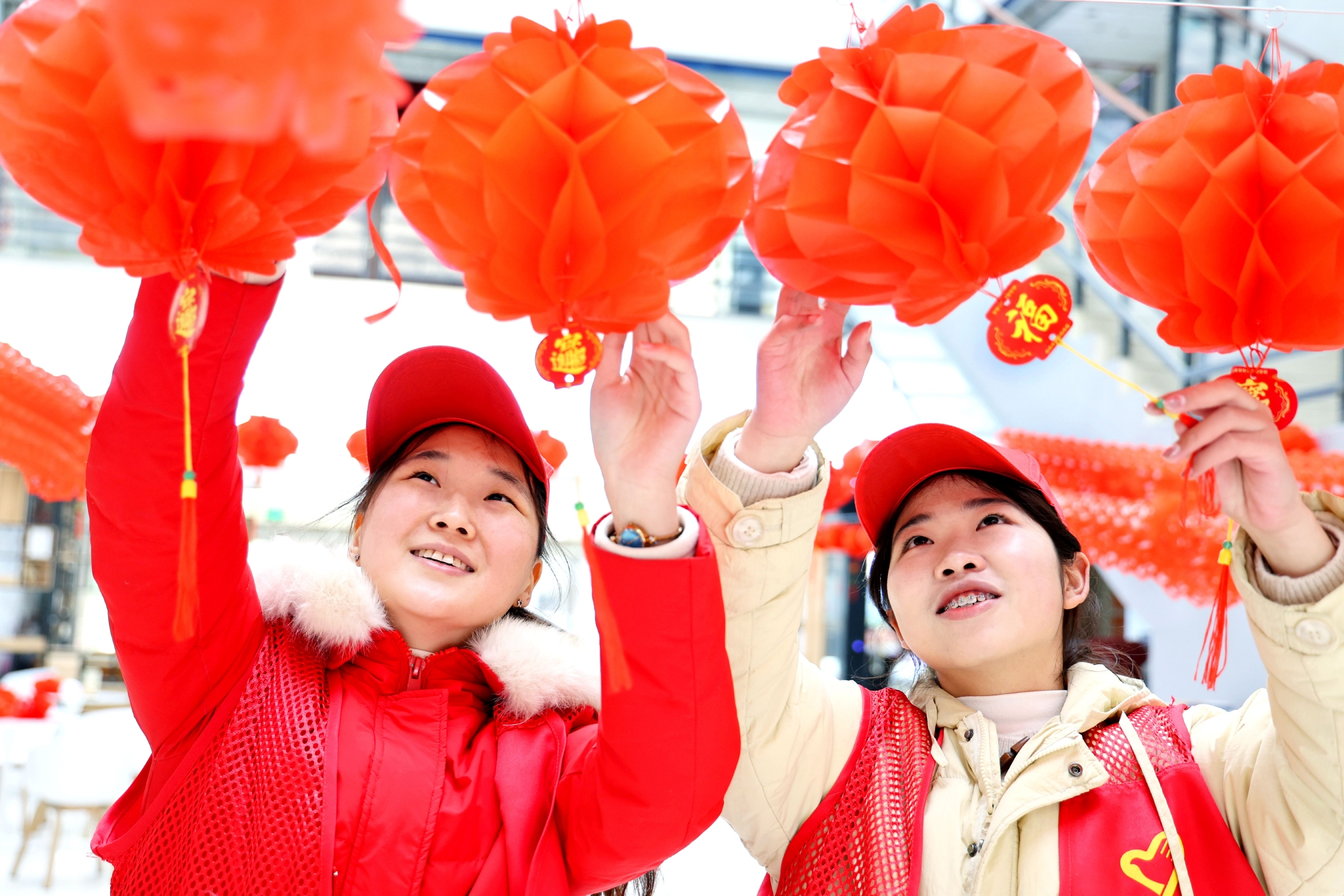 寒假大学生志愿者在安徽省淮北市图书馆一楼大厅整理悬挂拉花灯笼，迎接元宵节到来。通讯员 周方玲 摄