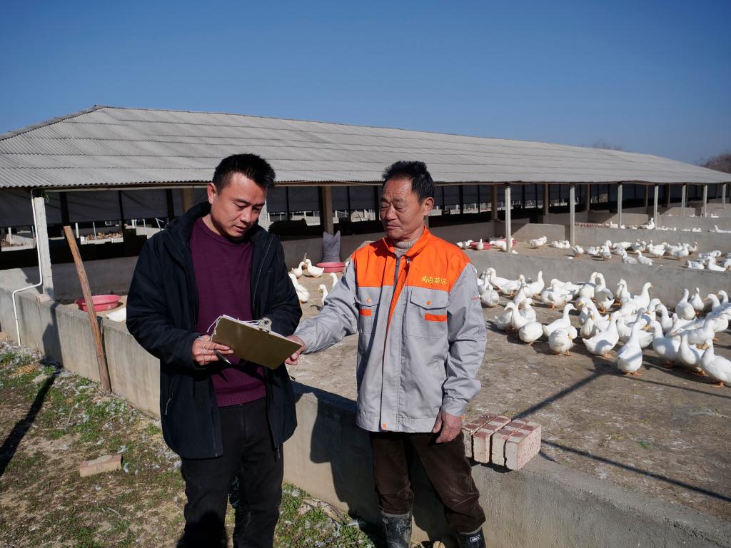 工作人员与谌寿生交流养殖技术。新华社记者郭杰文 摄