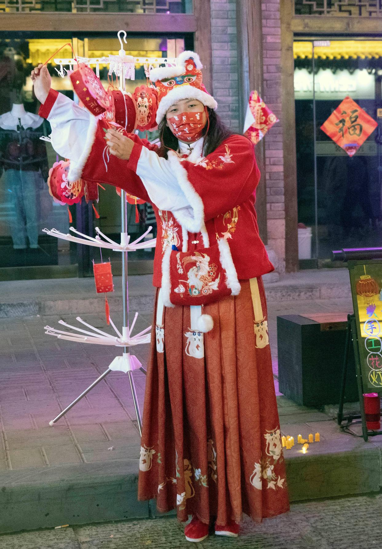 2月5日,在浚县古城街头,身着传统服饰的商贩向游客展示手工花灯.