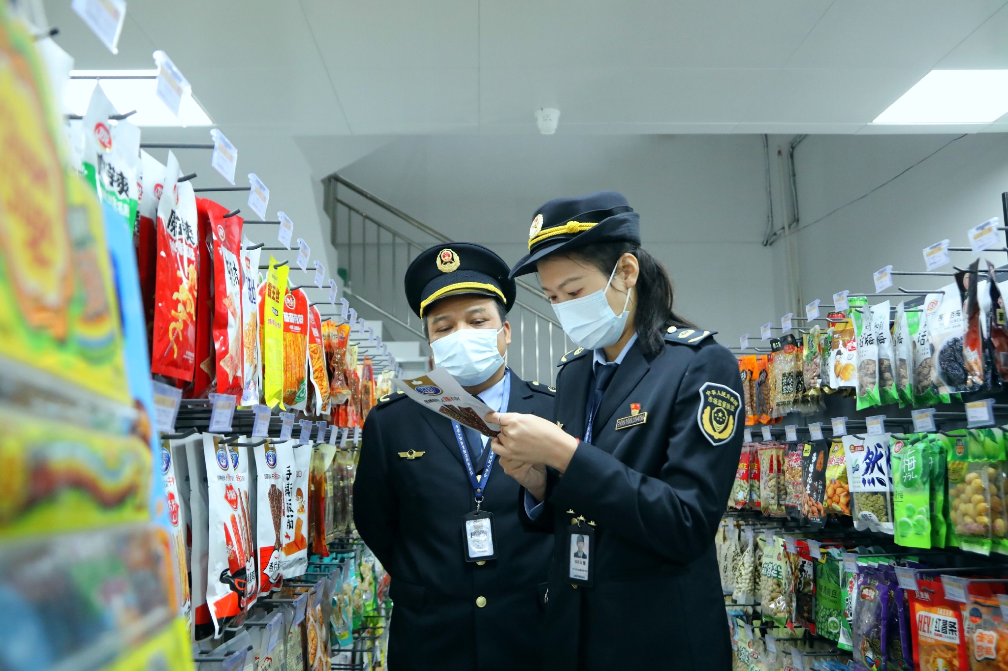 南宁市市场监管局经开分局执法人员对校园周边的便利店进行检查.