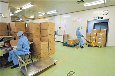 包装车间工人在运送包装好的药品.