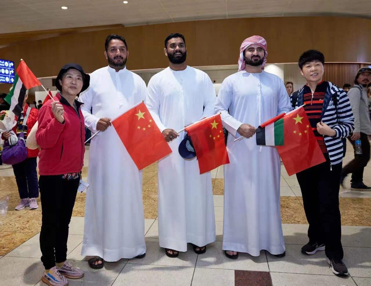 2月6日，中国搭客在阿联酋迪拜海外机场和服务人员合影。图片开端：新华社