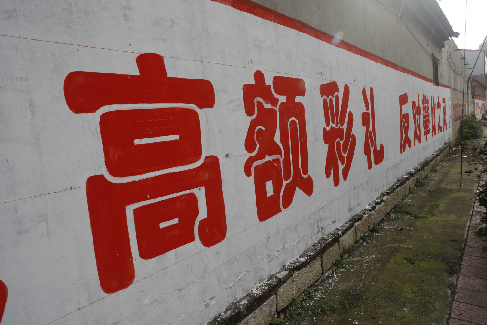 ↑农村墙上写着“拒绝高额彩礼、反对攀比之风”（资料图） 据IC photo