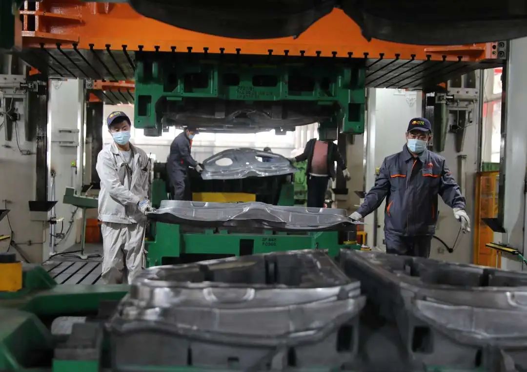 汽车车身模具有限公司生产车间,工人们对汽车车身覆盖板进行切边冲孔