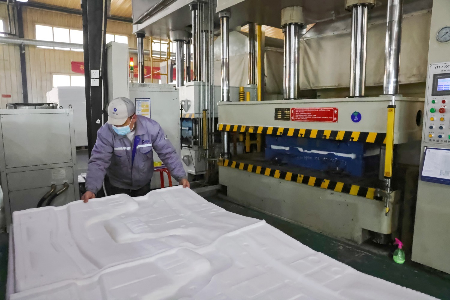 图为保定跃飞新型吸音材料有限公司的生产车间内,工人正在整理热压