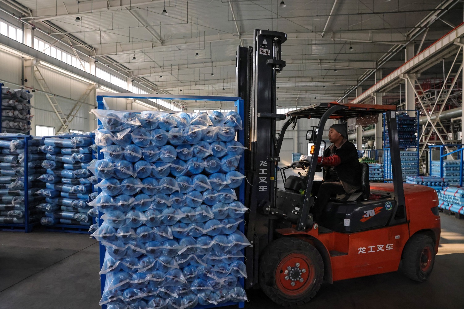 为在保定茂华塑料制品有限公司生产车间内,工人正在叉运打包好的产品