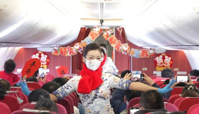 乘务员在新春主题的航班客舱内，表演团扇舞。（刘剑武 摄）