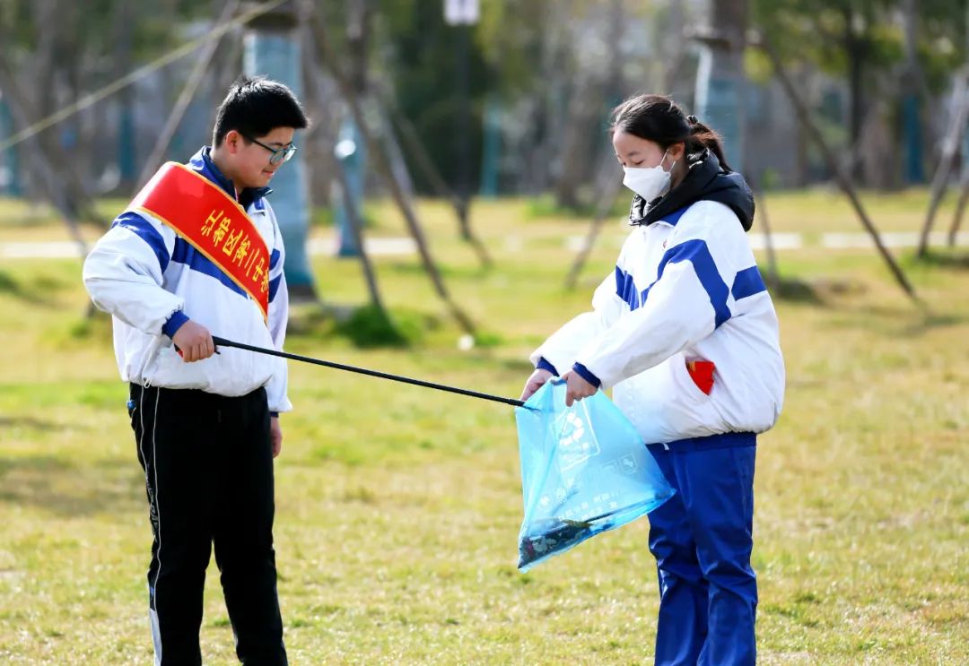 2022年3月5日，在江苏省扬州市江都区双拥公园，江都区第二中学学生在学雷锋主题活动中捡拾垃圾。新华社发（任飞 摄）