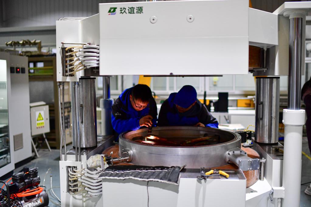 在四川玖谊源粒子科技有限公司生产车间内,两名技术人员在检查调试一