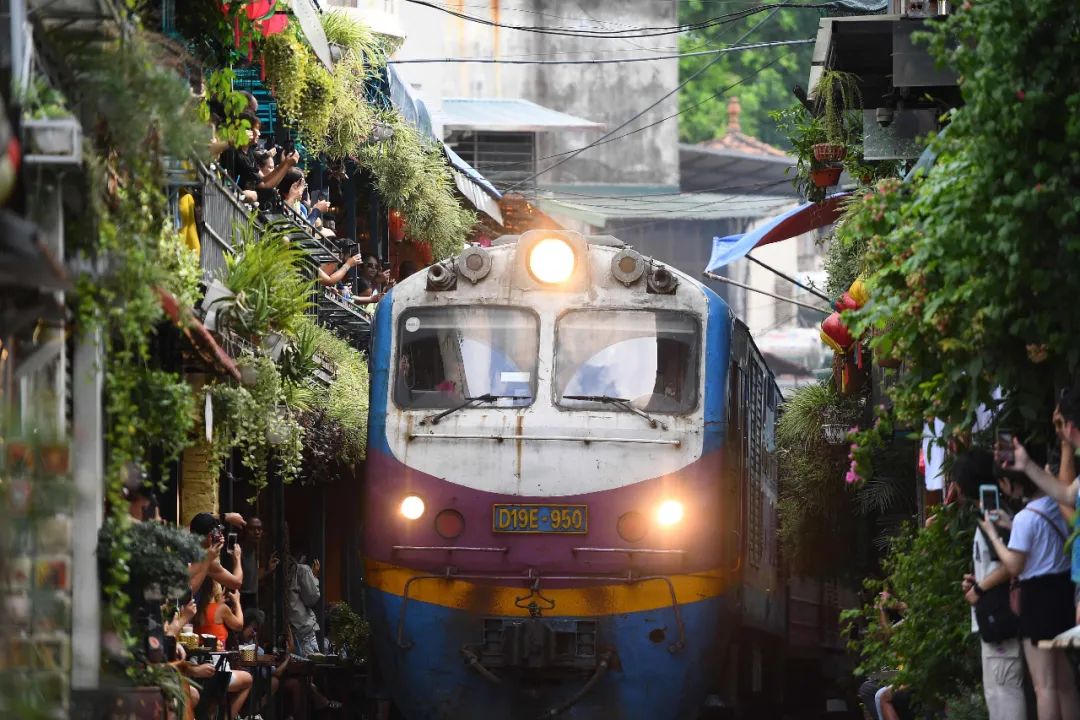 越南河内,游客在穿过市中心一个旧住宅区的铁路线上拍摄火车
