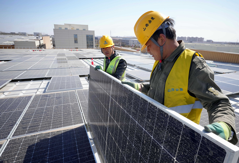工人在唐山市芦台经济开发区一家企业厂房屋顶上安装太阳能光伏发电板