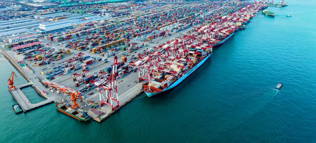 箱码头作业船舶穿梭往来,一辆辆集装箱运送车有序奔行,港口内一片繁忙