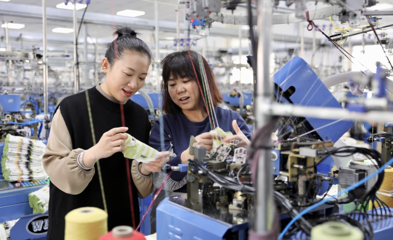 在村内的辽中区晟隆针织厂,马爽书记正在向生产车间的工人了解棉袜