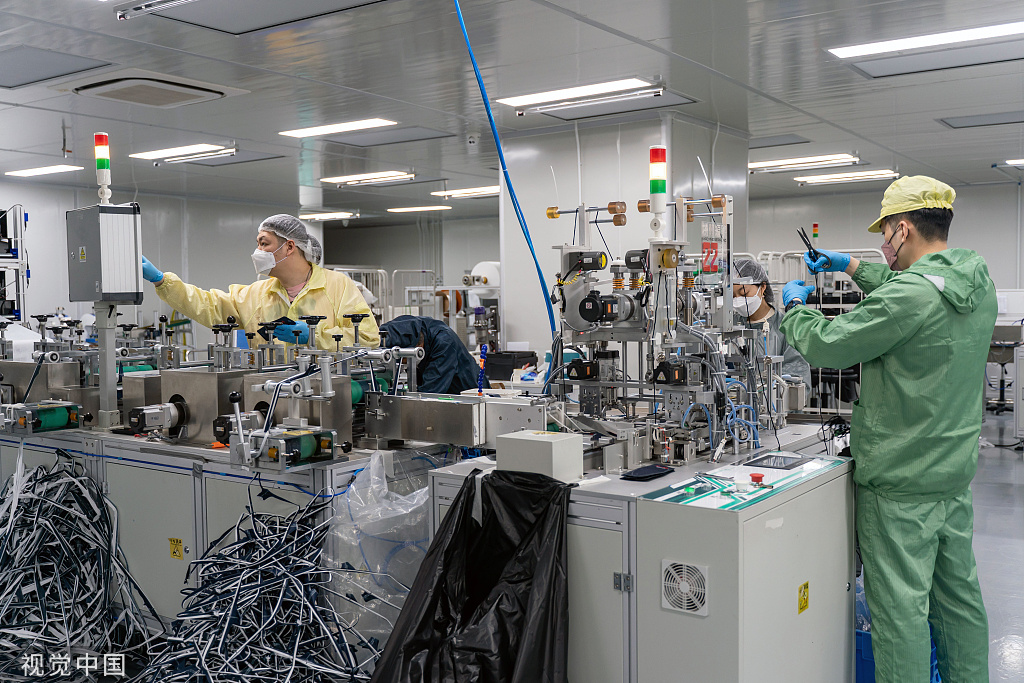 17日,香港一家工厂员工在防护口罩生产线上工作.