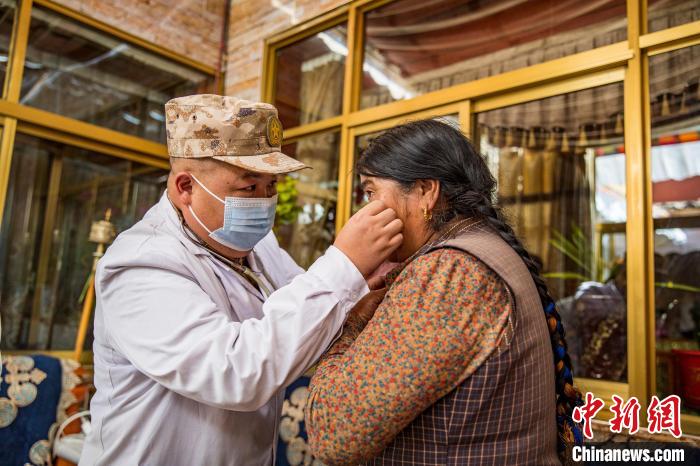 图为在西藏阿里地区札达县拓林镇，驻地部队军医为老人检查眼部情况。刘晓东摄