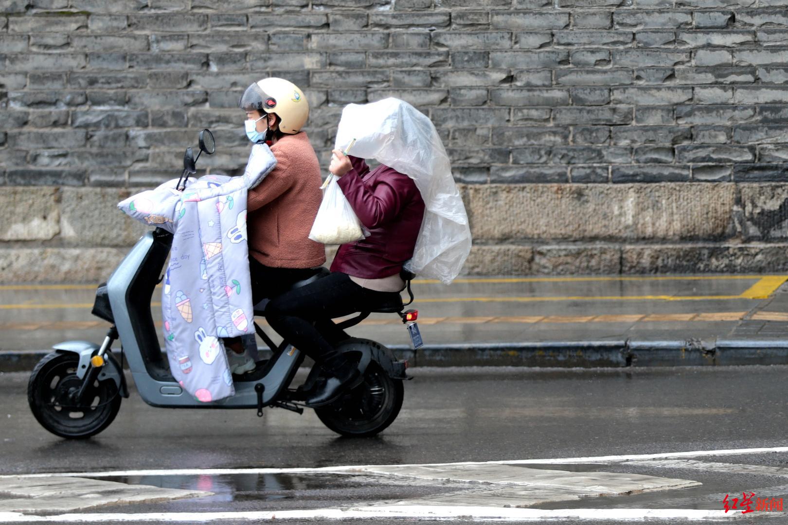 ↑3月23日，西安，市民冒雨出行 据视觉中国