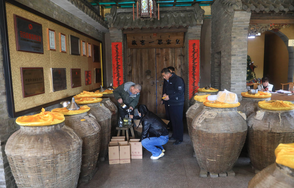 3月2日,张辉(左)在爱新觉罗祖家坊酒业有限公司为顾客打酒.