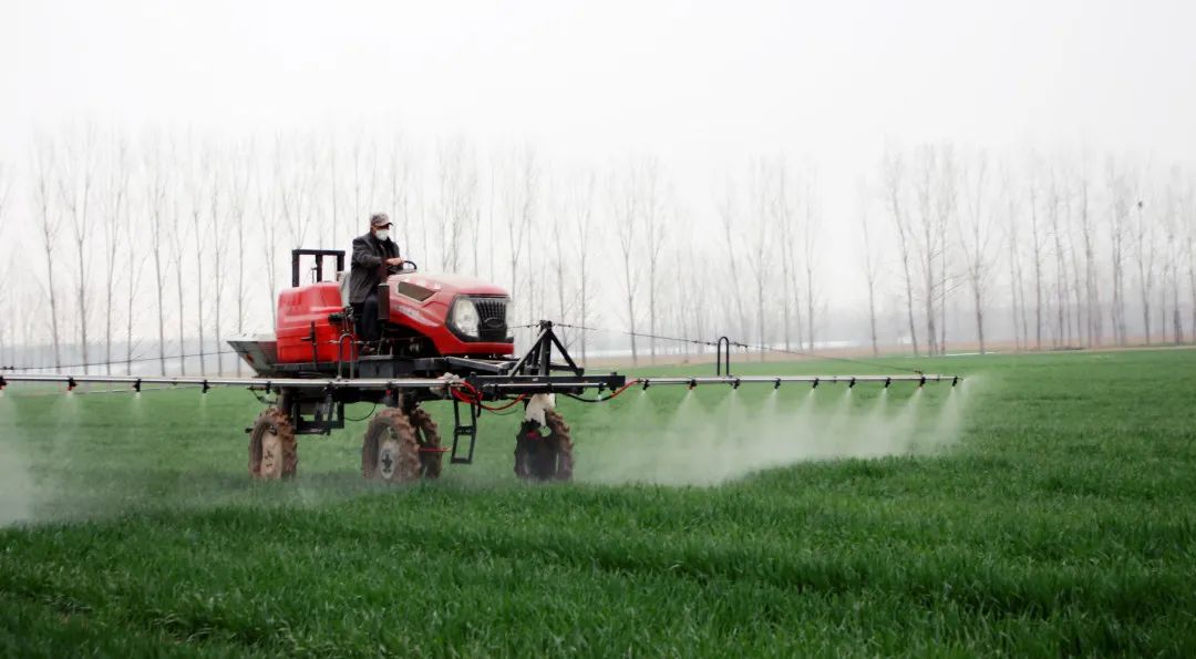 农民在操作喷杆喷雾机喷洒除草剂