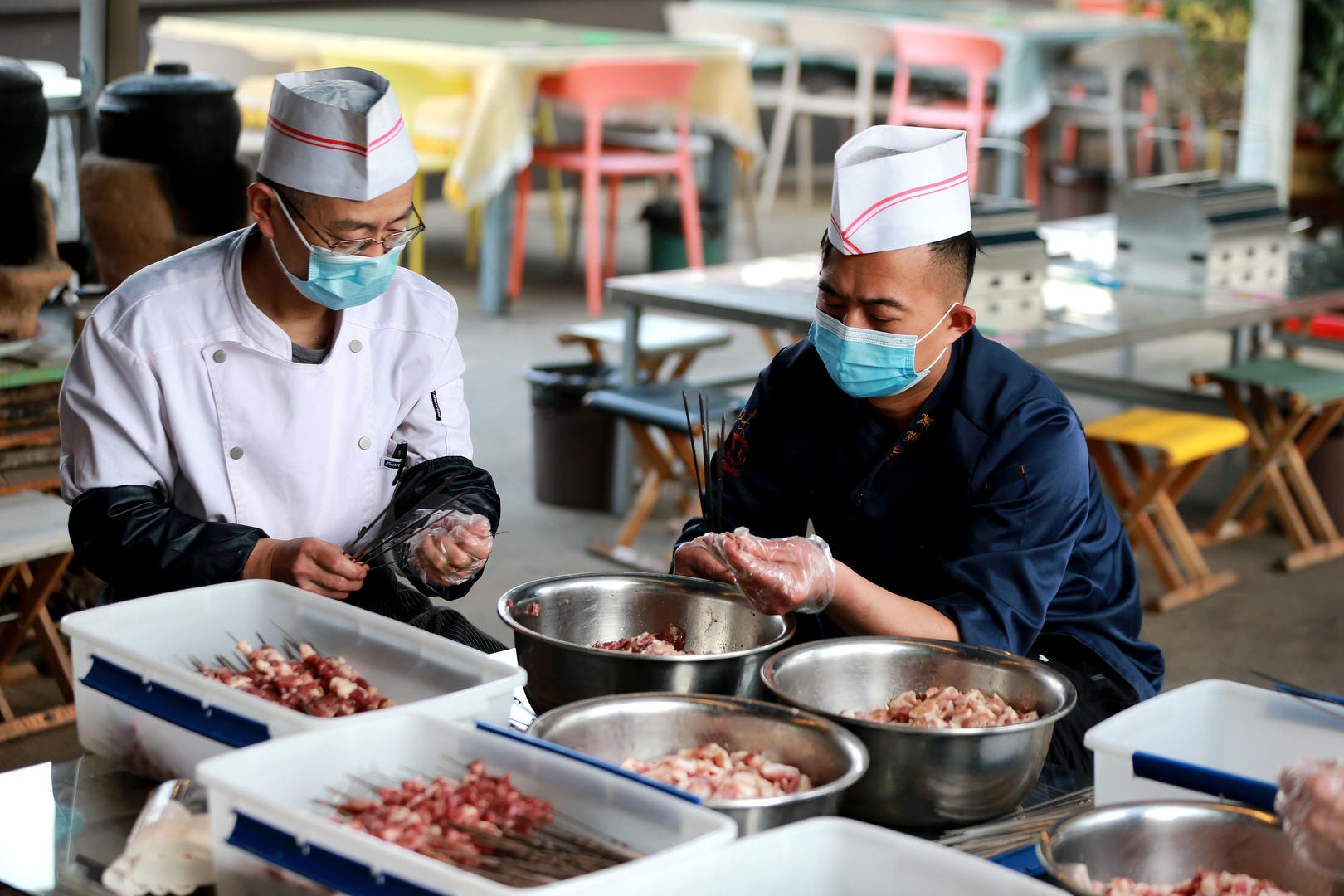 ↑一家烧烤店的厨师正在串肉串 图据视觉中国