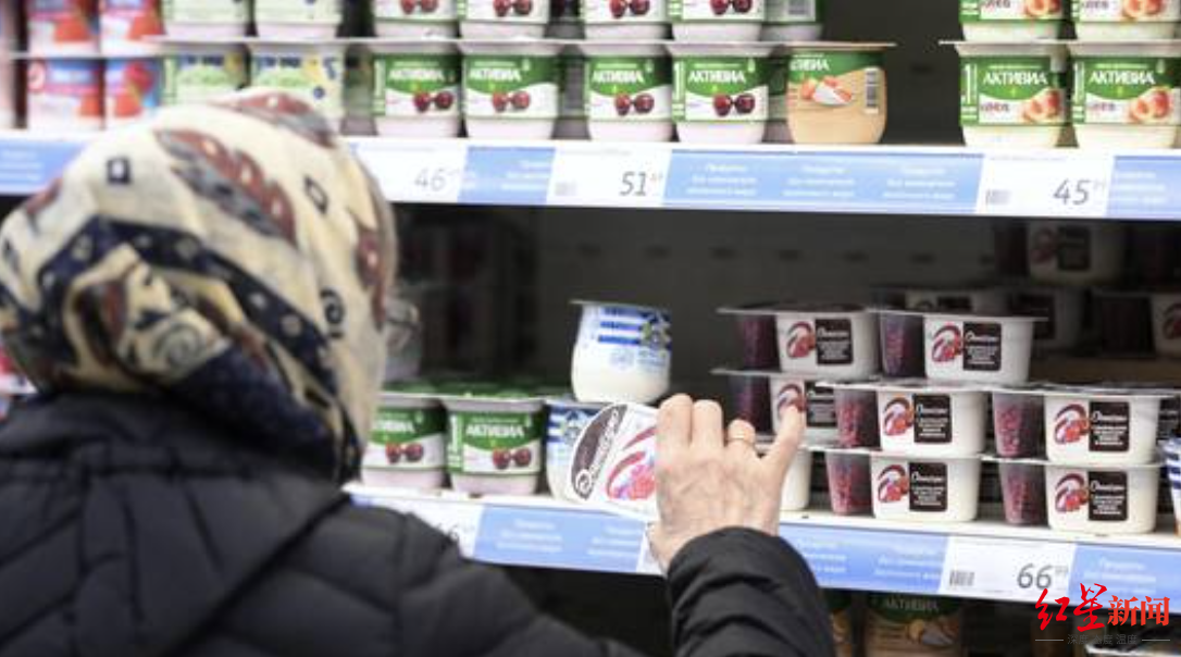 俄罗斯超市里，一名女性正在挑选达能生产的酸奶。资料图