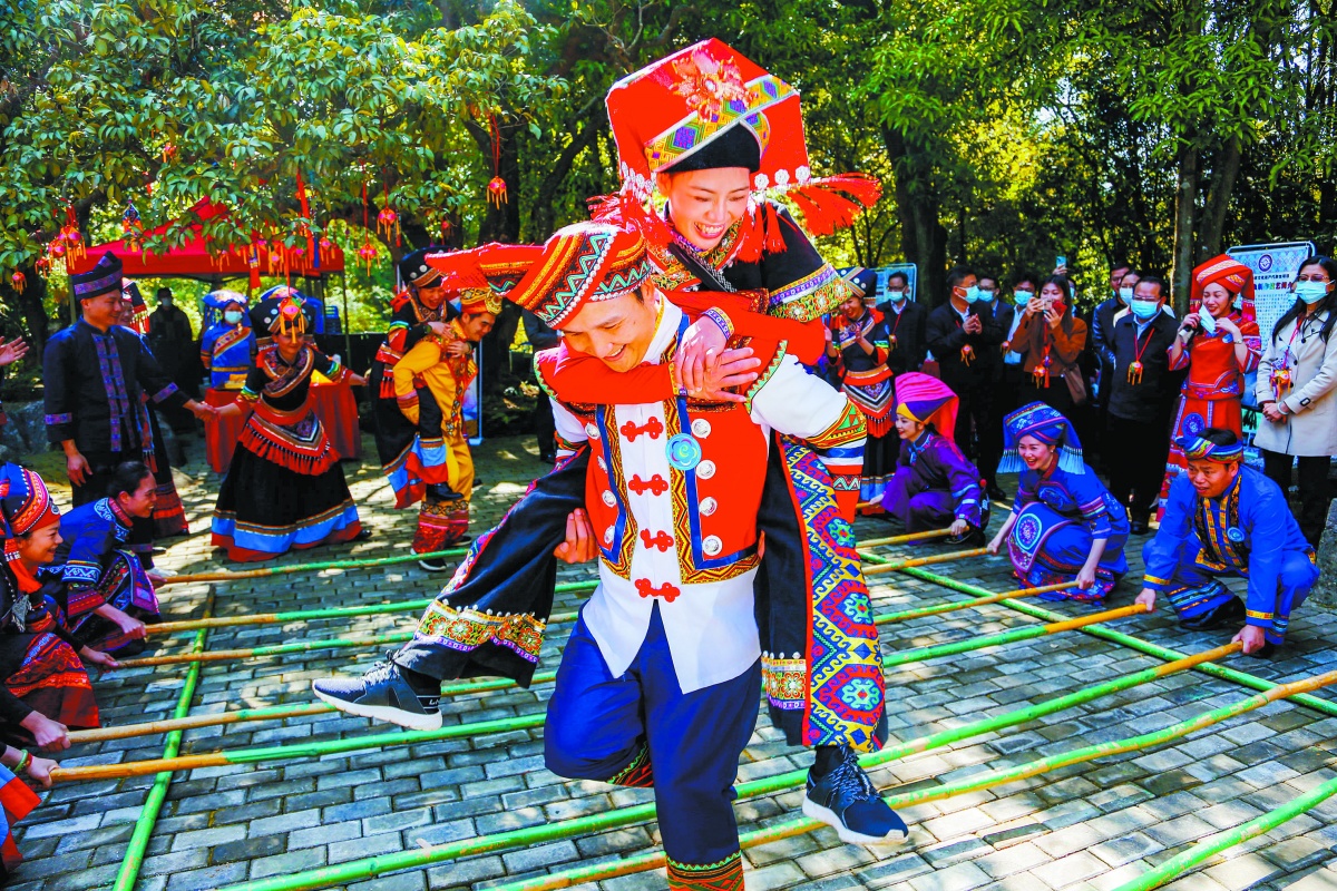 2022年南宁市武鸣区三月三活动现场,一位阿哥背着阿妹跳竹竿舞.