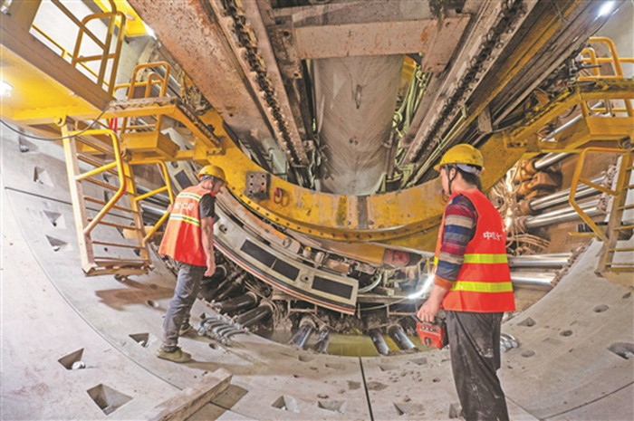 图为两名技术人员在贯通的地铁隧道内检查管片拼装质量.