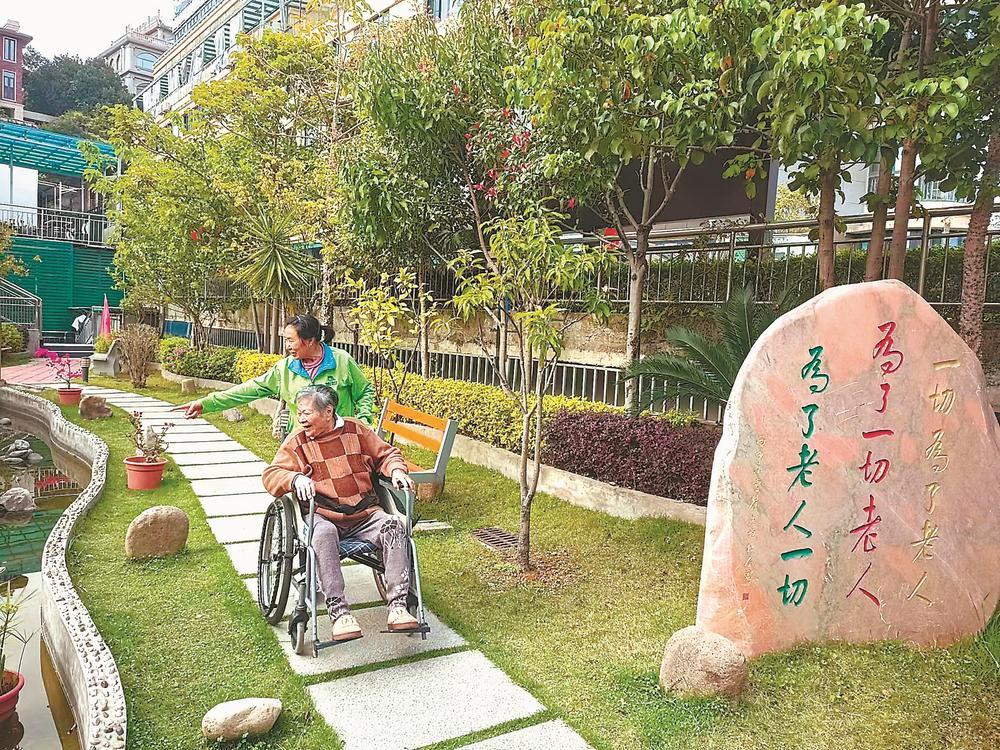 福州西园老年公寓护理人员推着老人在花园里散心.(资料图片)