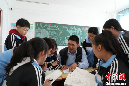 图为孟泽龙与学生们围坐在一起交流课堂知识.刘欢 摄