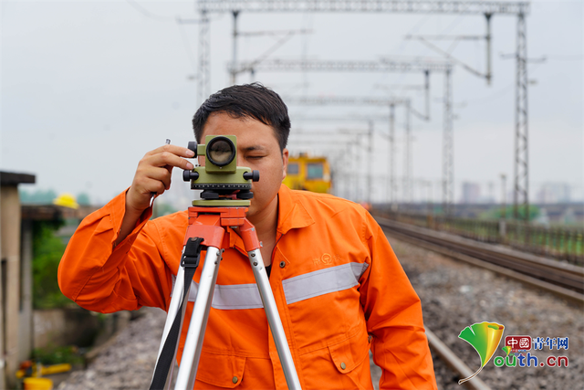 图为铁路青年职工对樟树大桥线路进行测量. 梁犇摄