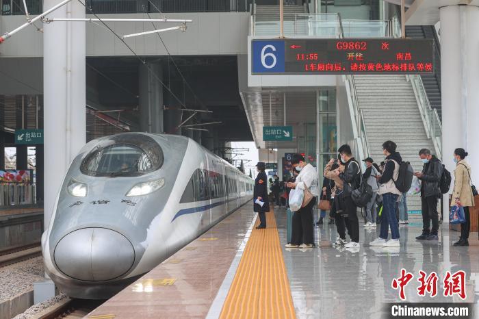 图为江西赣州西站,一辆动车组列车进站,旅客在站台上排队候车.