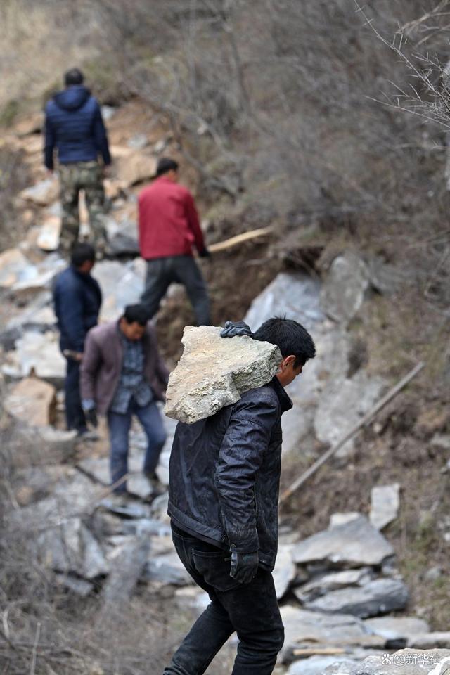 在山西省壶关县大峡谷镇青龙峡村,村民在修路现场搬运石头(2023年3月