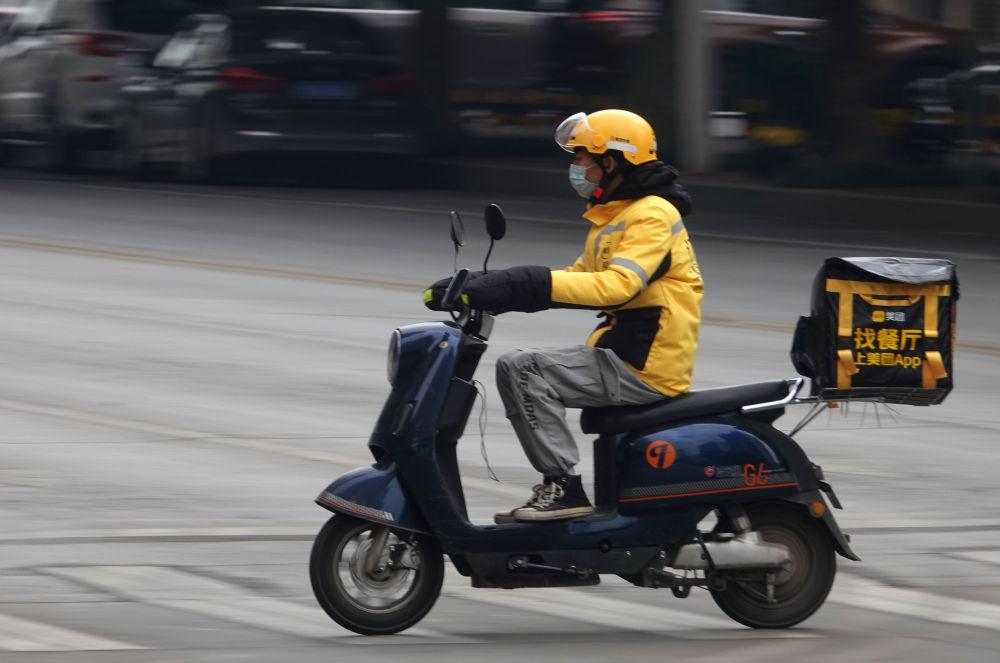 在广西南宁市高新区科德新苑路口,一名外卖小哥驾驶摩托为顾客送餐.