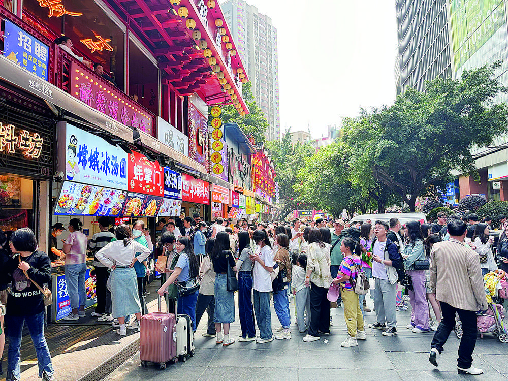 4月29日,解放碑八一路好吃街,众多游客品尝美食.据重庆日报