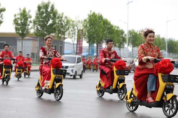 图注：山东阳信12对新人骑强国电单车参加集体婚礼