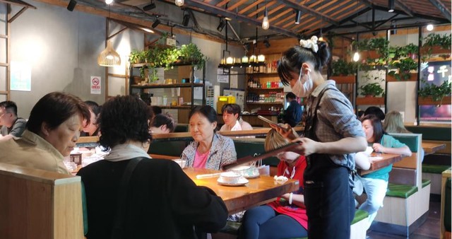 餐馆工作人员为顾客提供点餐人工服务.周学津 摄